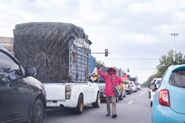 Vendors walk with flower garlands For cars parked on the roadside Intersection between cars waiting for traffic lights