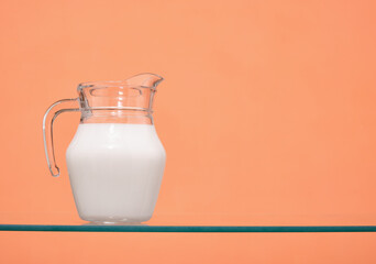 Fresh milk in a glass jug stands on the table. Useful vitamins and protein. Copy space for text.