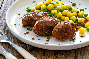 Baked pork cheeks in sauce with gnocchi and green peas on wooden table
