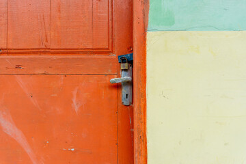 Rusty metal padlock in orange wooden door. Locked door