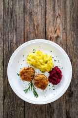 Fried pork meatballs with mashed potatoes and grated beets on wooden table

