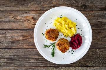 Fried pork meatballs with mashed potatoes and grated beets on wooden table

