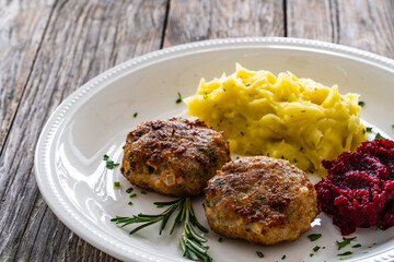 Fried pork meatballs with mashed potatoes and grated beets on wooden table


