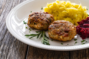 Fried pork meatballs with mashed potatoes and grated beets on wooden table


