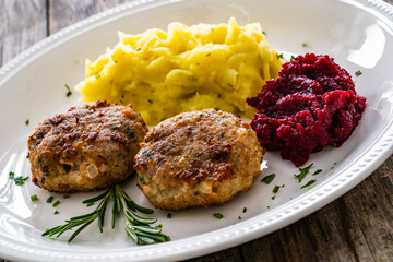 Fried pork meatballs with mashed potatoes and grated beets on wooden table

