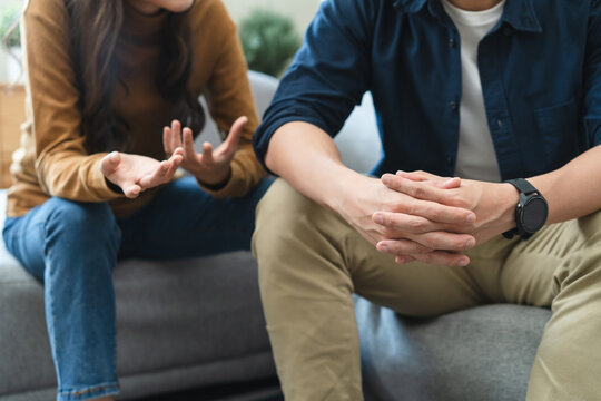 Family problem concept, Close-up hands of Asian wife sitting on sofa and husband sitting back to back in the living room at home have problems in a relationship and have an argument