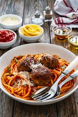 Spaghetti meatballs in tomato sauce on wooden table
