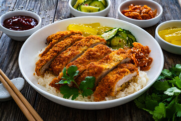 Torikatsu - crispy Japanese chicken cutlet with white rice and marinated vegetables on wooden table
