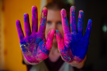 Women's palms covered with bright dry Holi paint. Hands covered in dry paint