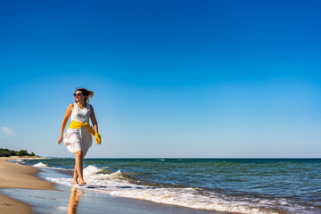 Beautiful mid adult woman walking, running on sunny beach
