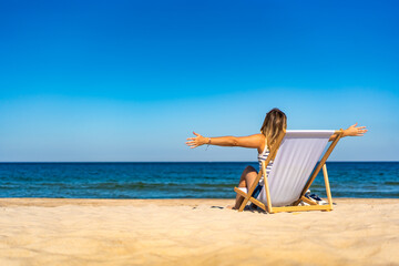 Woman relaxing on beach sitting on sunbed
