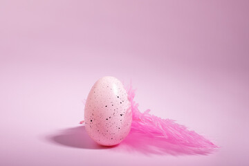 Easter egg and feather on pink background, holiday decoration, springtime celebration, DIY decor