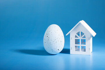 spring mortgage, Easter egg and house on blue background, springtime celebration, home decor,...