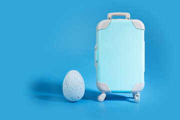 Easter egg and luggage on blue background, travel booking concept, season journey
