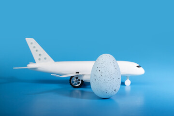 Easter egg and plane on blue background, avia theme, vacation decor, travel season