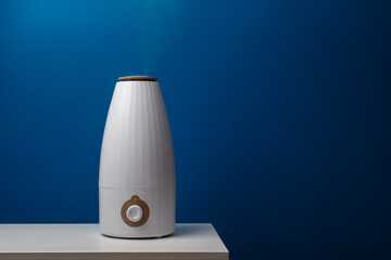 Air humidifier, blue background, modern vaporizer, home environment