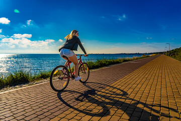 Mid adult woman riding bicycle at seaside

