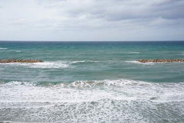 Strong currents and waves in the sea. Waves successfully crash into the stone breakwater.