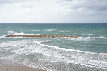 Strong currents and waves in the sea. Waves successfully crash into the stone breakwater.