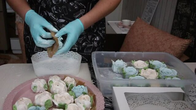 A woman tear off a zephyr from paper. Sprinkles it with powdered sugar. Spruce cones from zephyr and flowers from zephyr. Homemade zephyr. Slow motion.