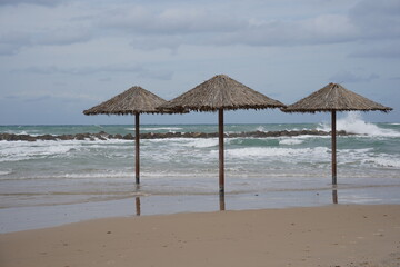 Sandy beach in winter. Waves flood the sandy shore with umbrellas.