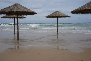 Sandy beach in winter. Waves flood the sandy shore with umbrellas.