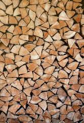 Firewood stacked near the wooden wall of old hut. Many chopped logs of firewood close up