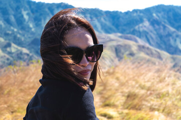 Close-up of a stylish asian woman with sunglasses admiring the view in a mountainous landscape,...