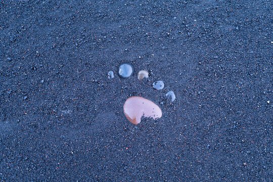Black sand and pebble as a background. Round stones on the beach. Photography for design. Textures in nature.