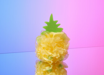 A shower washcloth in the shape of a yellow pineapple. Spa beauty and shower products.