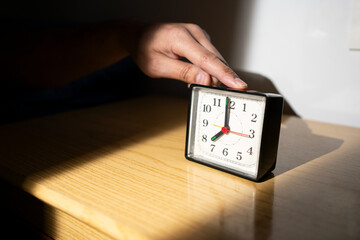 Man reaching for his alarm clock after waking up in bed at home - obrazy, fototapety, plakaty