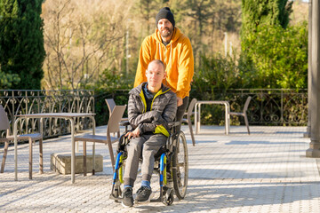 Disabled man with wheelchair and friends strolling in a park