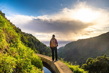 Tourist on Levada do Norte on the Portuguese island of Madeira. Levada irrigation canal. Hiking in...