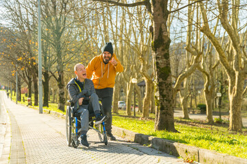 Caregiver pointing ahead talking to disabled man in a park