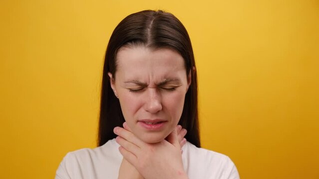 Close up portrait of unhealthy sad young woman holding hands over sore throat feeling discomfort. Painful neck and frowning, thyroid disorders, suffering sore throat, tonsils inflammation concept