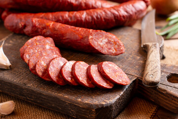 Smoked sausage on a wooden table with addition of fresh aromatic herbs and spices, natural product from organic farm, produced by traditional methods