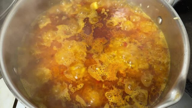 Pilaf during preparation in stainless steel pot on stove top