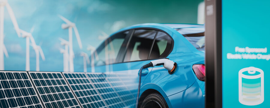 A blue electric car is charging and has a picture of solar panels.