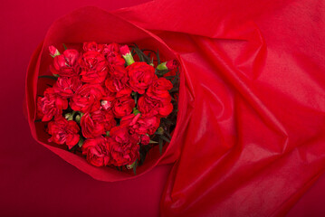 上からの赤い背景の赤いカーネーションの花束