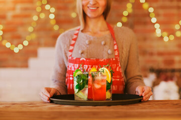 Young pretty woman with red and green cocktails on tray