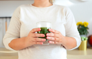 Female hands holding cup of green matcha tea closeup