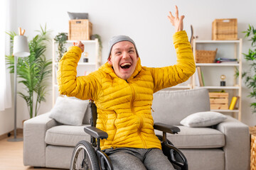 Happy disabled man in wheelchair raising hands in joy celebrating - obrazy, fototapety, plakaty