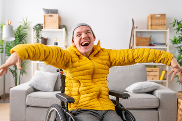 Happy disabled man in wheelchair laughing at camera at home