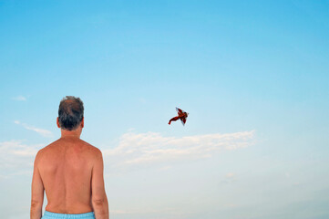 Caucasian senior man watching a kite flying in the sky