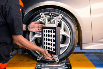  Close-up of car mechanics installing sensors during suspension adjustment and automobile wheel...