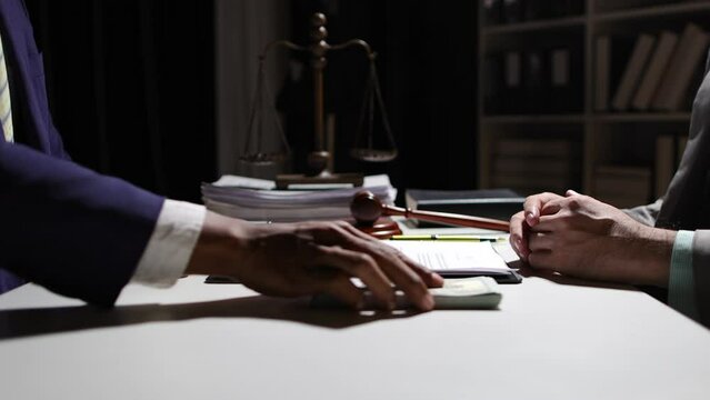 Corrupt lawyer accepts bribes from an unknown man in the dark. Businessman in the dark tries to bribe officials.
