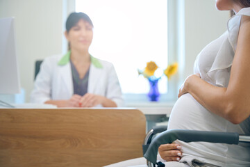 Partial pregnant woman during consultation at blurred female gynecologist