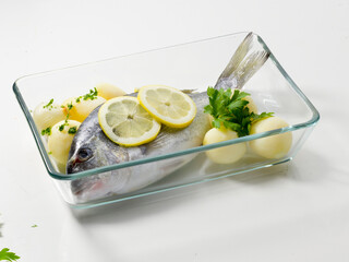 Besugo con patatas, perejil y limón sobre fuente para cocinar. Sea bream with potatoes, parsley...