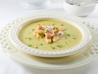 Crema de salmón en plato de porcelana blanco sobre mesa. Hake in green sauce on plate and white background