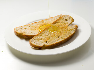 Baguette con aceite de oliva sobre plato con fondo blanco, desayuno. Baguette with olive oil on silver with white background, breakfast.
